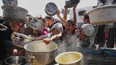 Crowds of children holding pots waiting desperately for food aid in Gaza